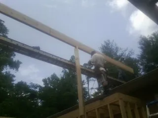 Carpenter setting a ridge beam over a new addition frame — Ice Dam Removal by Roofing Brothers in Danielson