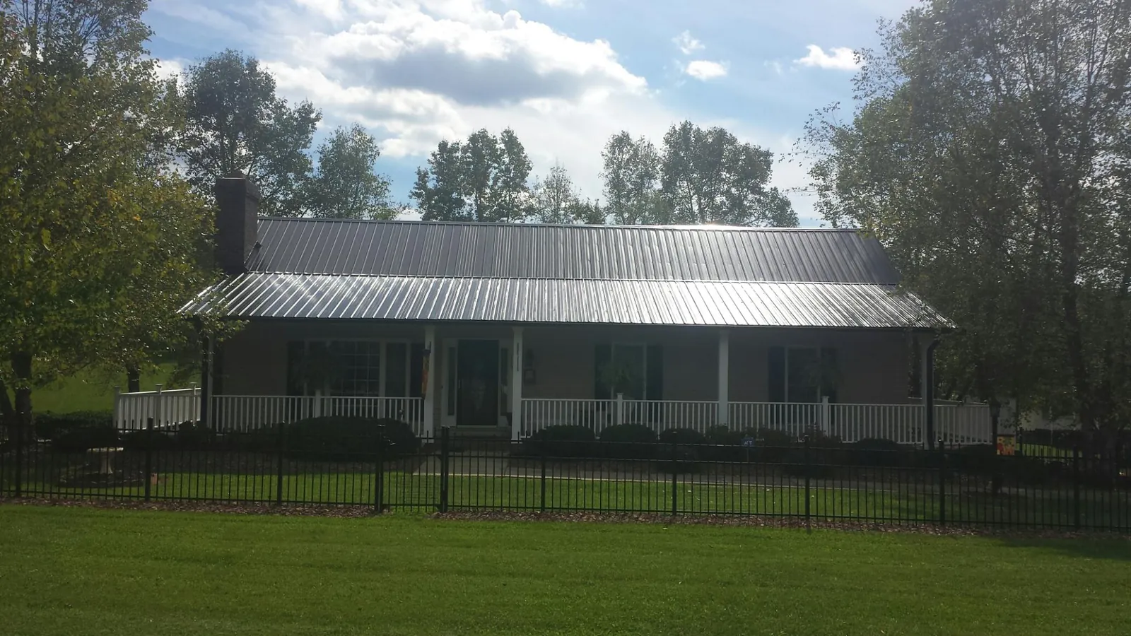 Gray metal roof on a brick ranch with a full width front porch — Gutter Guard Installation work by our crew in Danielson