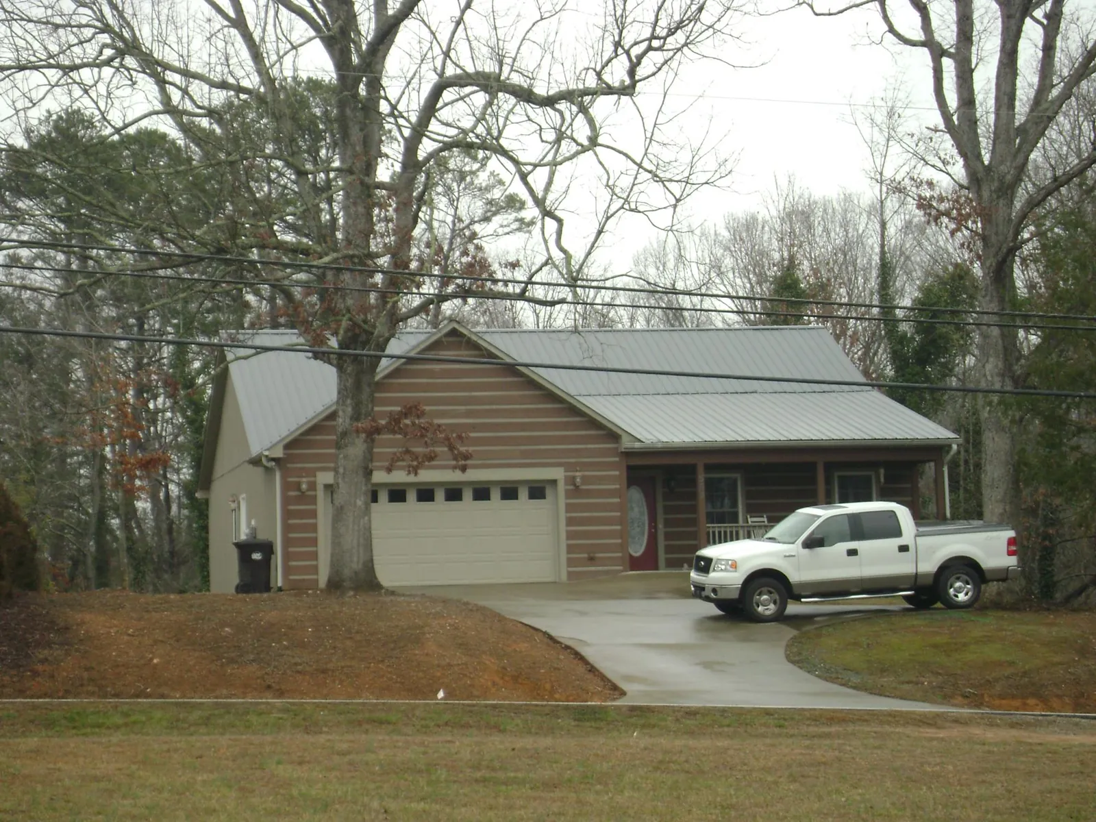 Gray metal roof on a log sided house with an attached two car garage in Danielson