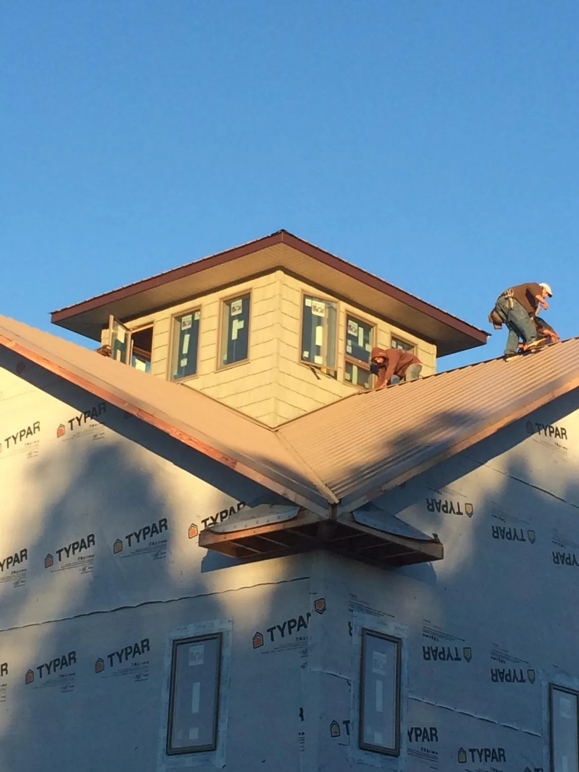Roofers working around a rooftop cupola on a new metal roof at sunset — Roof Waterproofing in Danielson by Roofing Brothers